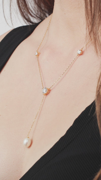 Model trägt y-Kette in Gelbgold mit Moissanit und Süßwasserperle der Marke Lunore